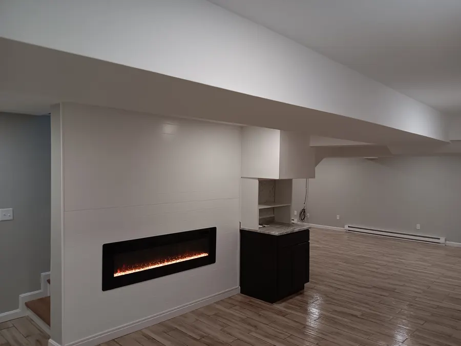 Finished basement with linear fireplace and wood-look floors